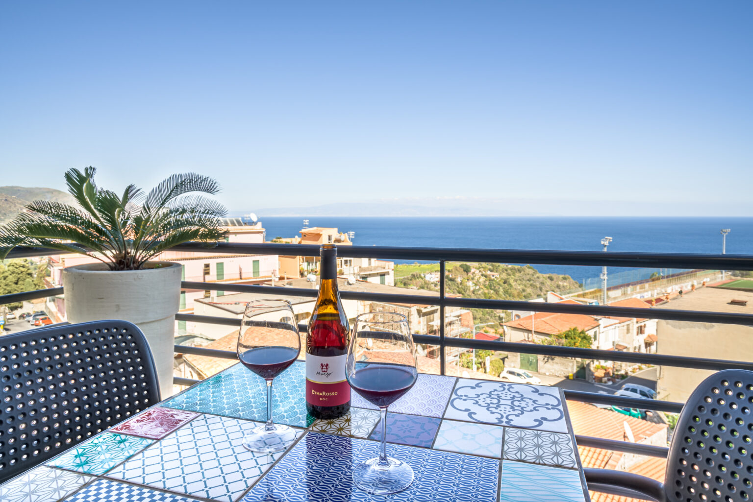 Calice di vino in terrazza con vista sul mare di Taormina